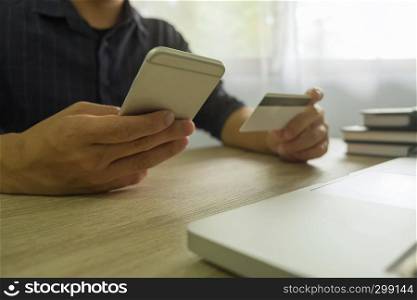 Man holding credit card and using smartphone for payment shopping online.