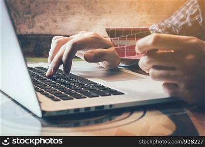 Man holding credit card while using laptop in home office.