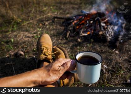man holding cup coffee campfire