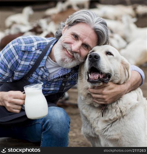 man holding cup goat milk while playing with dog