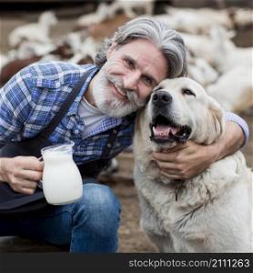 man holding cup goat milk while playing with dog