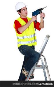 Man holding drill whilst stood on ladder
