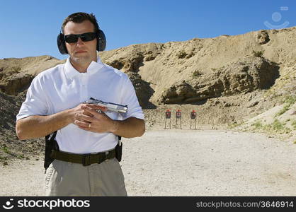 Man holding hand gun at firing range, portrait