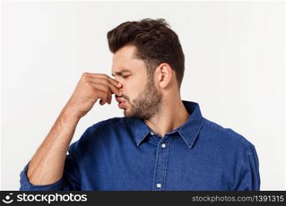 Man holding his nose against a bad smell isolated over grey background. Man holding his nose against a bad smell isolated over grey background.