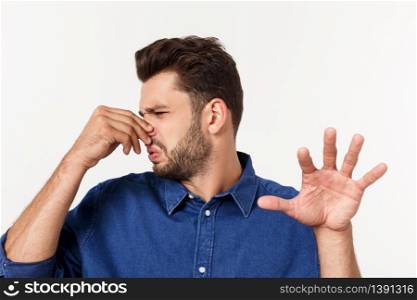 Man holding his nose against a bad smell isolated over grey background. Man holding his nose against a bad smell isolated over grey background.