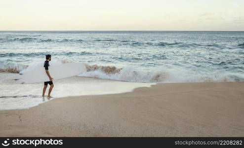 man holding his surfing board long shot