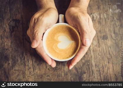 man holding hot cup of coffee, with heart shape