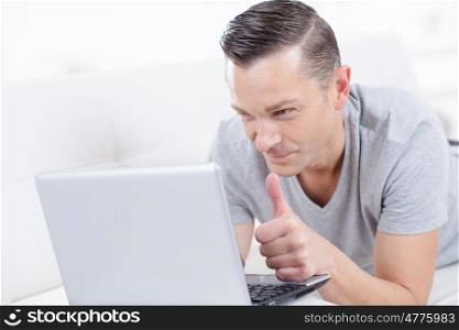 man holding laptop and thumbs up indoor