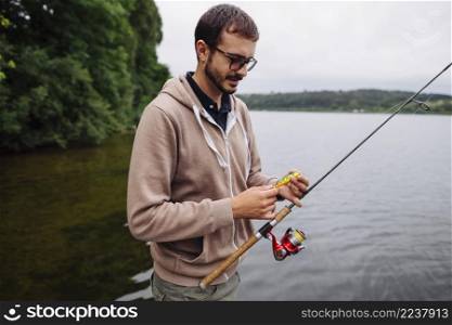 man holding lure fishing rod near lake