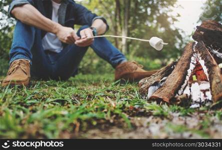 man holding marshmallow campfire in the forest