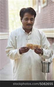 Man holding milk canister and counting rupees