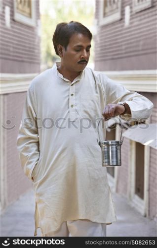Man holding milk canister and looking at watch