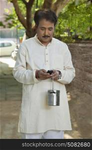Man holding milk canister and using cell phone