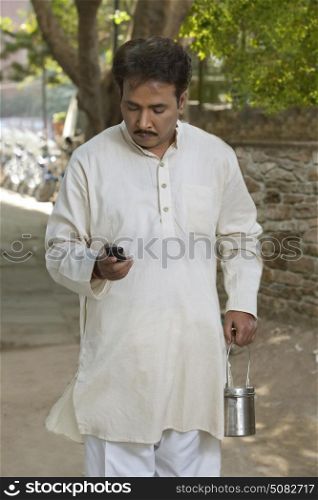 Man holding milk canister and using cell phone