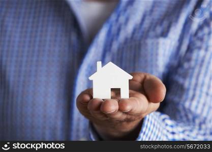 Man Holding Model House In Palm Of Hand