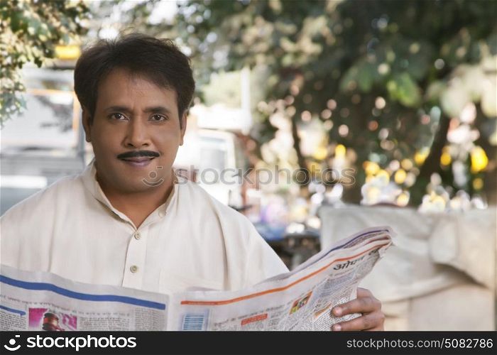 Man holding newspaper and looking at camera
