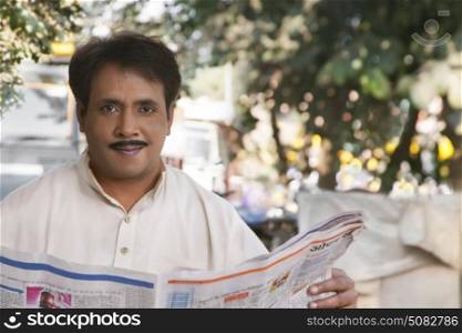 Man holding newspaper and looking at camera