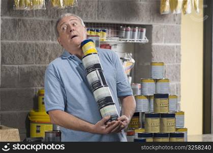 Man holding paint cans and struggling in a hardware store