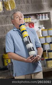 Man holding paint cans in a hardware store