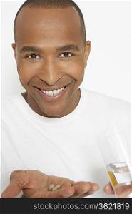 Man holding pills and glass of water, portrait