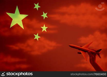 Man holding plane toy with chinese flag in background