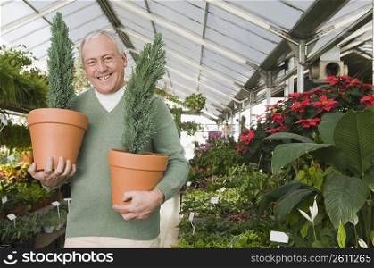 Man holding potted plants in a garden center