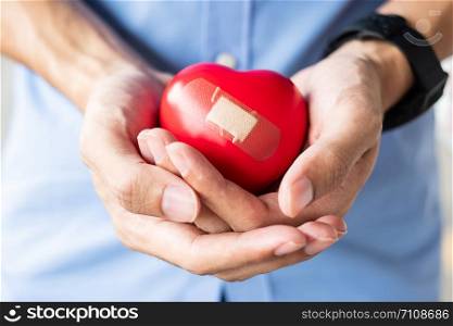 man holding Red heart shape on wooden background. Healthcare, life Insurance and World Heart Day concept
