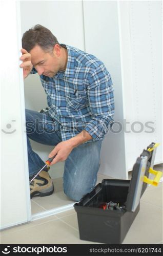 Man holding screwdriver working on doorframe