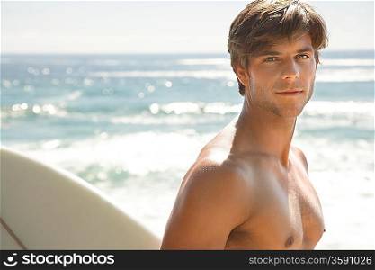 Man holding surfboard by ocean head and shoulders