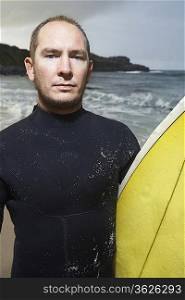 Man holding surfboard on beach, close up, portrait
