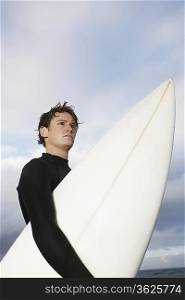 Man holding surfboard on beach, side view, low angle view