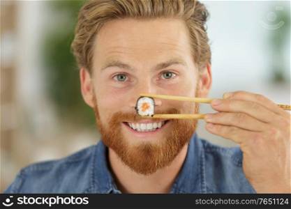 man holding sushi with chopsticks