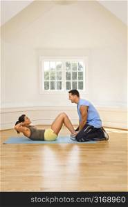 Man holding woman&acute;s feet down as she does sit up exercises.
