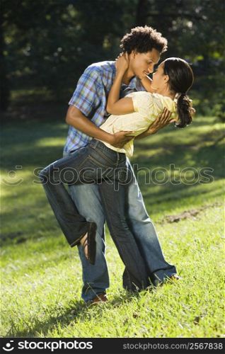 Man holding woman and dipping her down seductively while looking into her eyes.