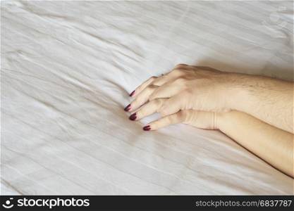 Man holding woman hand on white bed, couple sexual concept