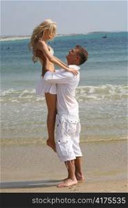 Man holding woman near the beach