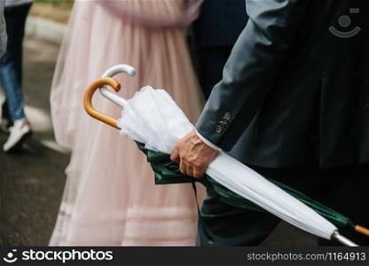 Man holds a white closed umbrella from the rain close up. Man holds a white closed umbrella from the rain