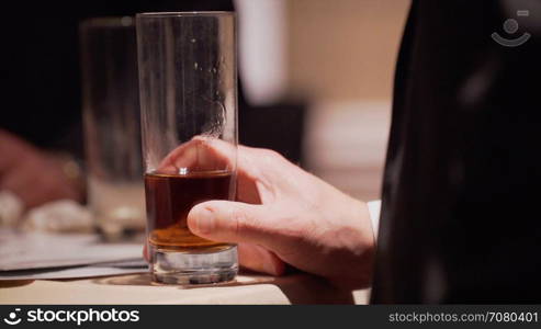 Man holds an alcoholic drink at a conference