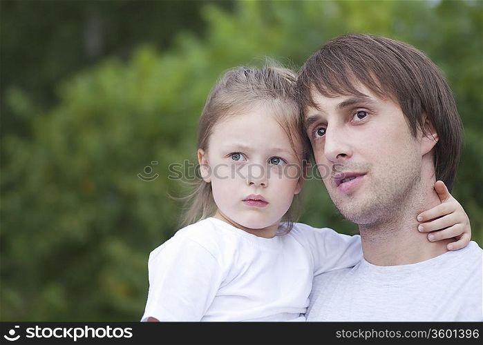 Man holds girl with her hand round his neck
