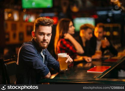 Man holds glass of beer at the bar counter in a sport pub, happy leisure of football fan