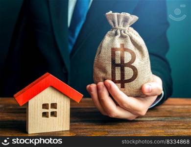 Man holds out a thai baht bag near the house. Bank approval for issuing a mortgage loan. Property appraisal. Home purchase, invest in real estate. Favorable terms and conditions, low interest rate.