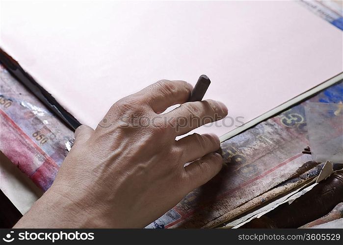 Man holds pastel preparing to draw