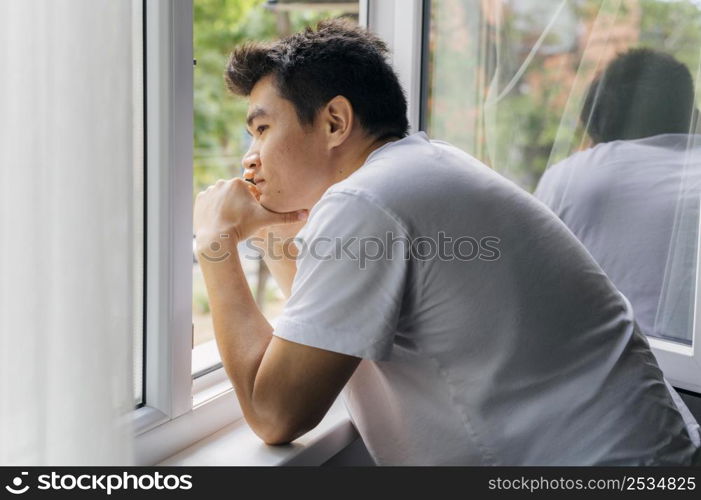 man home during pandemic looking through window outdoors