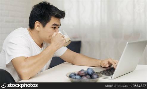 man home during pandemic using laptop having coffee
