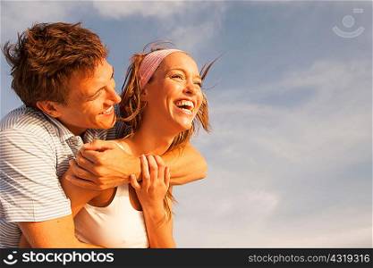 Man hugging girlfriend against blue sky