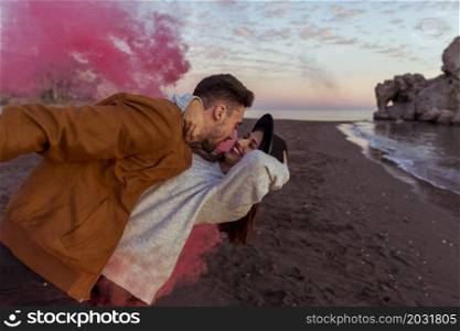 man hugging woman with pink smoke bomb sea shore