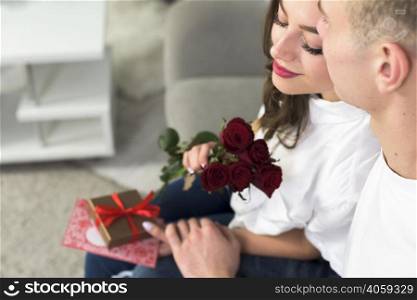 man hugging woman with red flowers couch