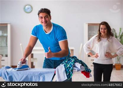 Man husband ironing at home helping his wife