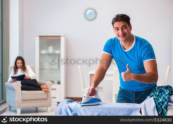 Man husband ironing at home helping his wife