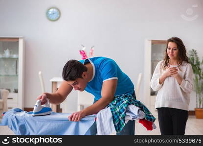 Man husband ironing at home helping his wife